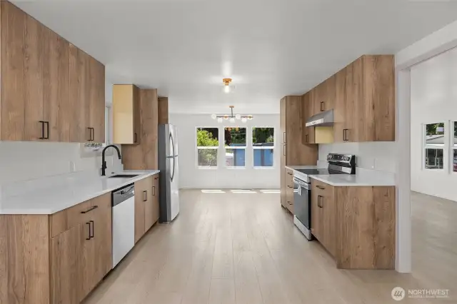 Another view of kitchen and dining area with living area and front door to the right