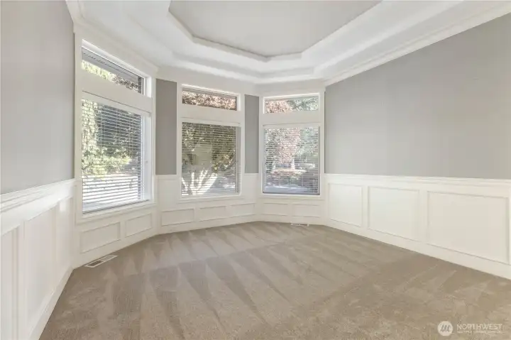 The dining room features a built-in buffet with two display shelves, gorgeous chandelier and accent lights, bay window, wainscoting, coved ceiling and easy access to both the kitchen and formal living room.