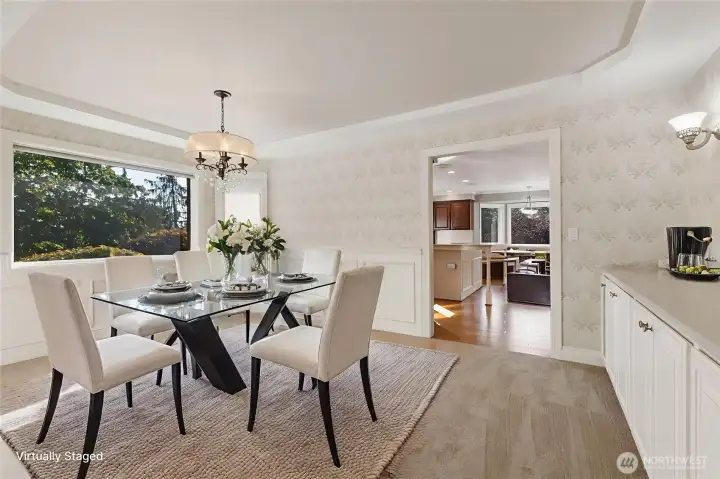 The dining room features a built-in buffet with two display shelves, gorgeous chandelier, accent lights, bay window, wainscoting, coved ceiling, and easy access to both the kitchen and formal living room.