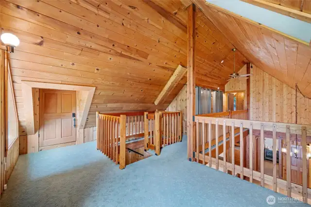 Upstairs is an open landing, with an extra half bath, more under-eaves storage (behind the door), storage along the walkway (behind the curtains), and another bedroom at the end of the walkway.