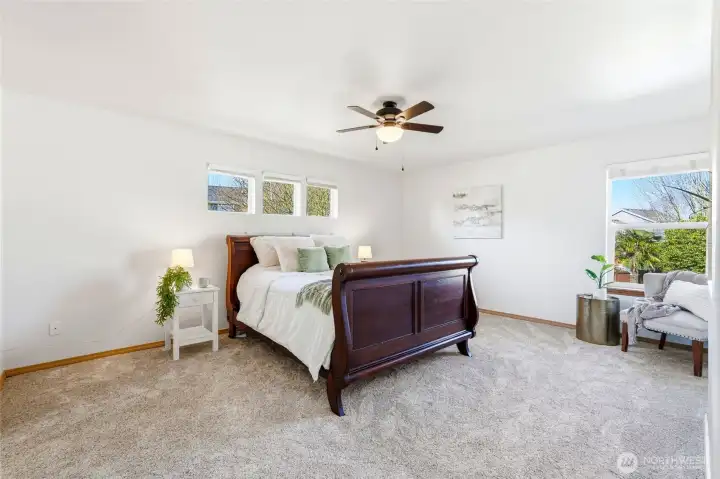 The expansive primary suite feels like a true retreat. There’s plenty of space for a king-sized bed and additional seating. Natural light enhances the calm and airy atmosphere.