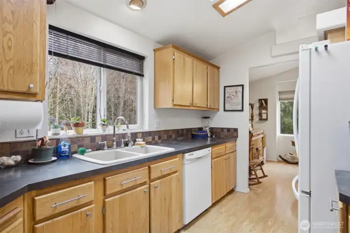 Another view of the kitchen with the hardwood cabinets and white appliances.