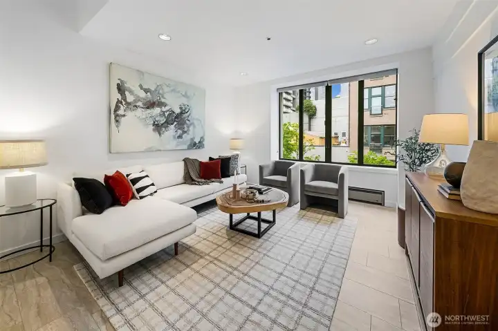 Living room is East-facing with the porcelain tile floors carried through and large windows for natural light.