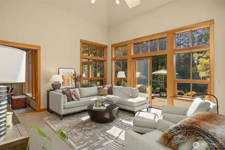 Large windows open to serene backyard views with mature trees visible from all rooms