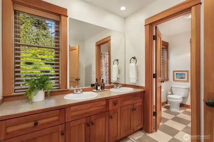 The hallway main bathroom with double sinks, marmoleum flooring, and a separate room with tub/shower combo