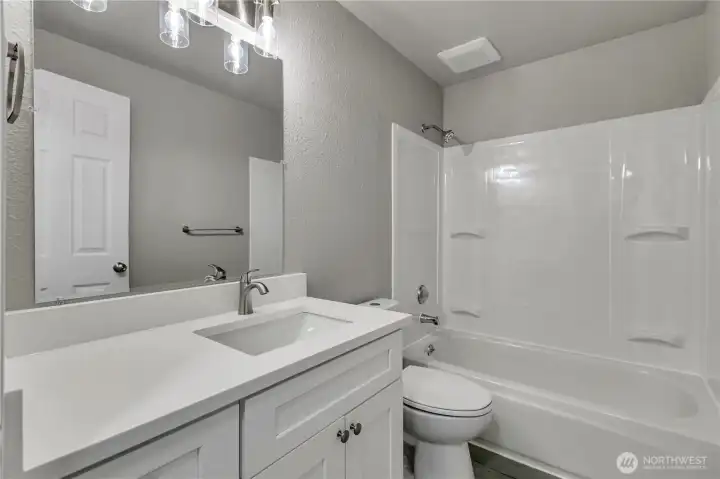 Totally remodeled bath with new shaker cabinet, quartz counters with drop in sink and new toilet, and new shower surround