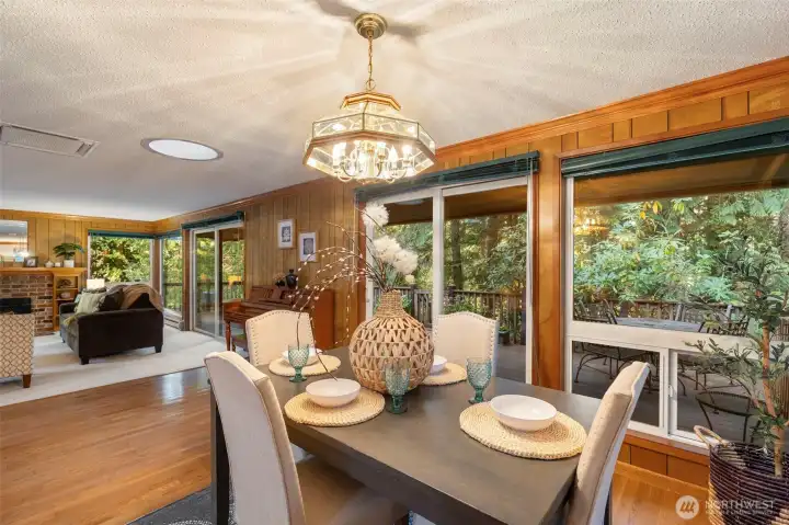 Wall of windows opens to expansive deck surrounded by nature