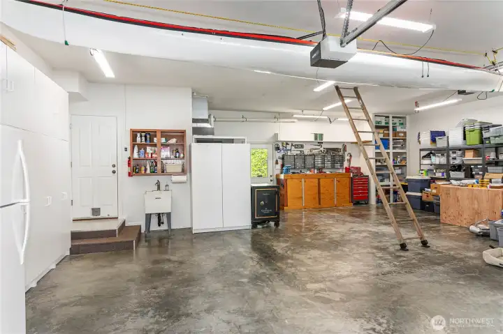 Oversized, three car garage with tall ceilings and garage door, lots of cabinets and access to more storage space above Oversized, three car garage with tall ceilings and garage door, lots of cabinets and access to more storage space above