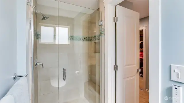 Walk-in tile surround shower with small bench and niche in this primary bathroom.