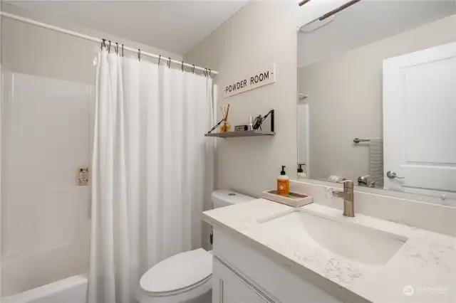 Hall bath offers newer vanity, quartz countertop, tiled tub surround, ceramic tiled flooring, toilet, and light fixture.  All updated nicely.