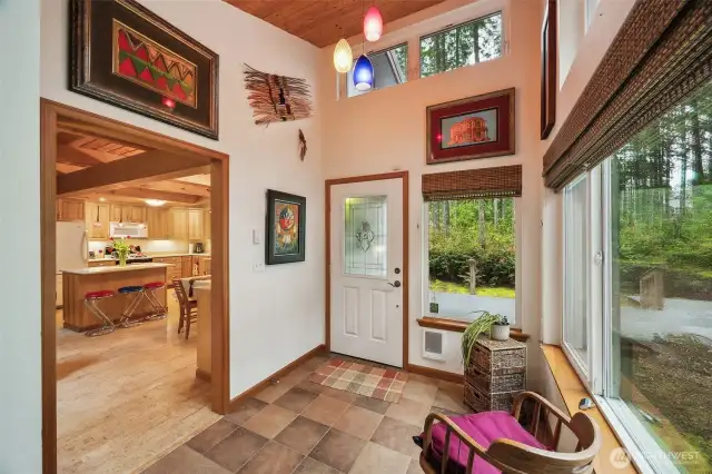Vaulted foyer with wood ceiling, pendant lights, ceramic tile floor & wall of windows!