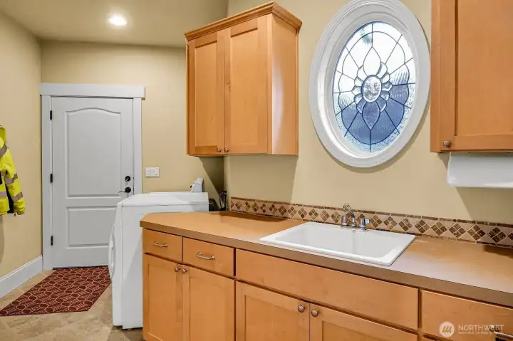 Large main floor laundry room with cabenters, utility sink and tons of storage.  Washer and Dryer (gas) stay.
