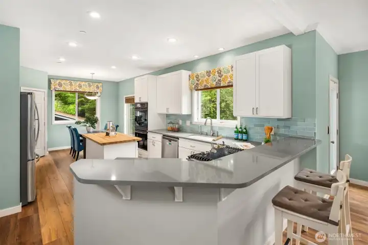 The remodeled kitchen has quartz counters, subway tile backsplash, bar seating, and a walk-in pantry. The remodeled kitchen has quartz counters, subway tile backsplash, bar seating, and a walk-in pantry.