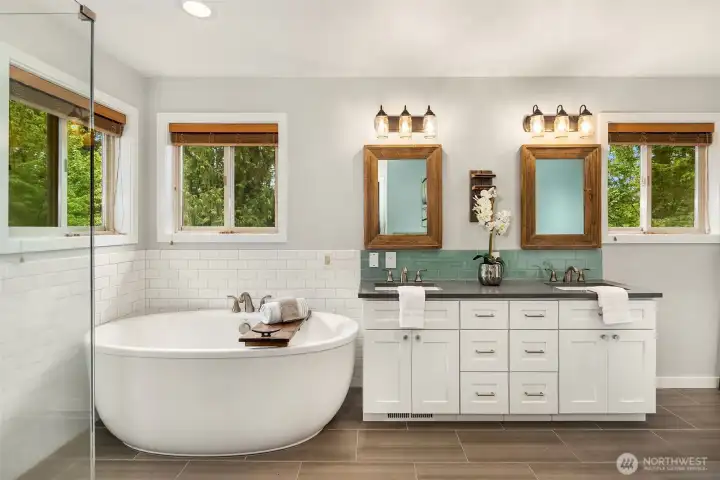 The remodeled primary bath feels like a private retreat with a freestanding soaking tub, dual vanity, stylish wood-framed mirrors, and park-like views that make you feel surrounded by nature. The walk-in closet is just to the right. The remodeled primary bath feels like a private retreat with a freestanding soaking tub, dual vanity, stylish wood-framed mirrors, and park-like views that make you feel surrounded by nature. The walk-in closet is just to the right.