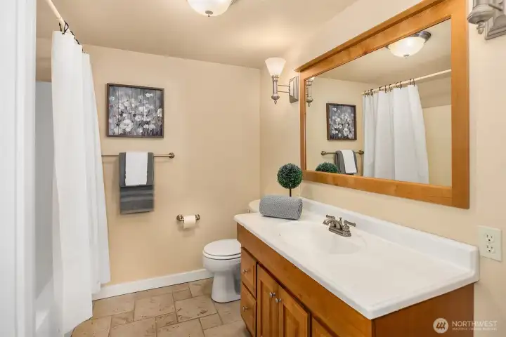 Full lower-level bath features tile flooring, a large vanity, and a shower/tub combo. Full lower-level bath features tile flooring, a large vanity, and a shower/tub combo.