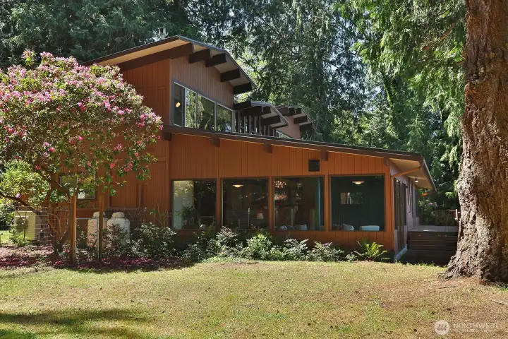 East side of home. This wall of windows belongs to the generously sized Family Room with a propane fireplace and sliding glass doors to the waterside of the home.