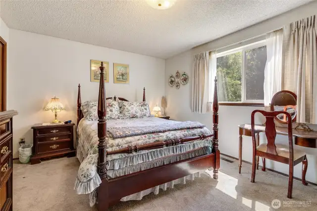 A primary bedroom with a sunny window- a nice way to wake up in the morning