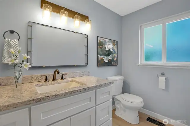Lovely updated full bath features a granite top vanity paired with bright white cabinetry for a light and bright bath.