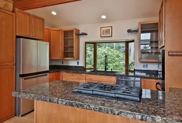 Propane cooktop/range, granite countertops, and quality cabinetry. Bay window keeps that theme of being close to nature and welcoming light consistent throughout this home.