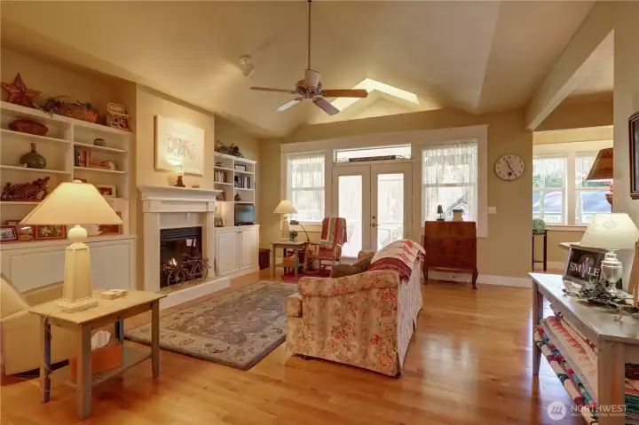 Vaulted Great Room features Built-ins, Hardwood Flooring, Ceiling Fan, Gas Fireplace and Opens to the Sun Room. Breakfast Nook and Kitchen to the Right.