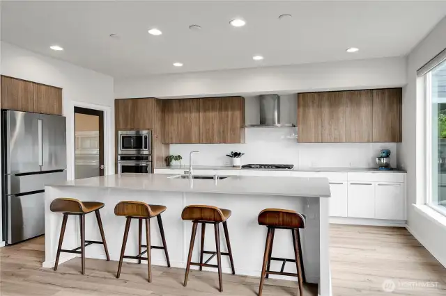 The palatial kitchen is a chef’s dream and features a gigantic quartz center island and a long breakfast bar and pull-out garbage & recycle bins tucked underneath.