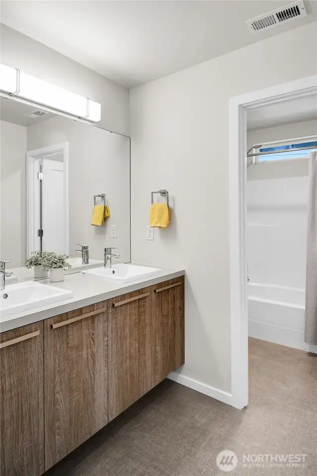 A full bath is centrally located between the bedrooms and is divided into two sections for the ease of multiple users.  There is a long vanity counter with two raised square sinks. Section two is where the bathtub/shower and toilet are located.      A walk-in linen closet in the main hallway provides additional storage.