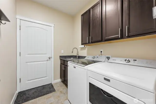 Utility room with washer and dryer, utility sink and cabinets for storage