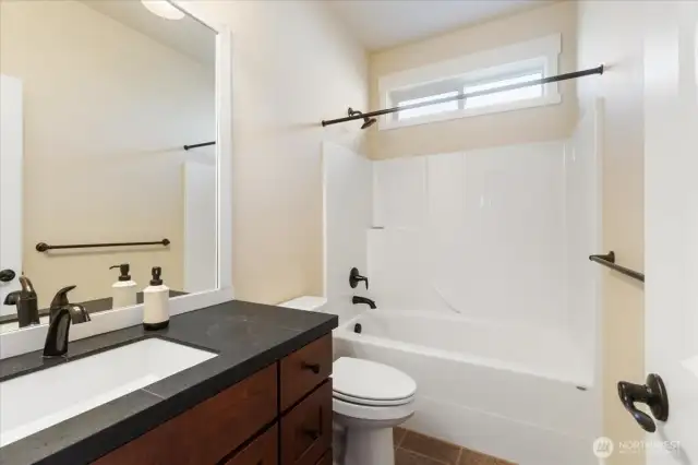 Stylish full bathroom featuring elegant tiled floors and a sleek granite vanity, this bathroom combines durability with timeless design.