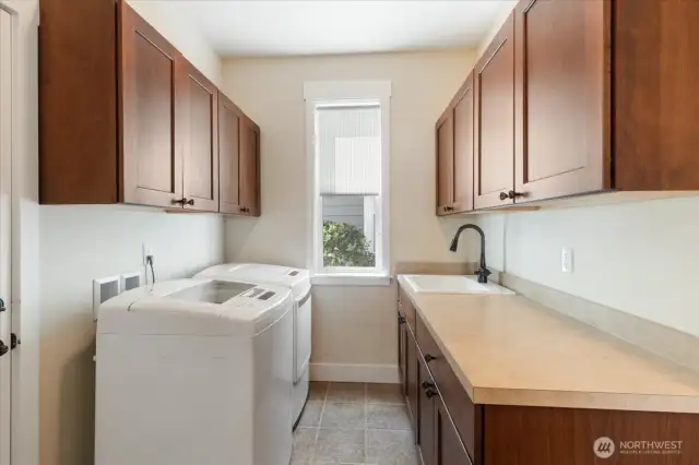 This spacious utility room offers abundant cabinet storage and comes complete with a high-quality LG washer and dryer—included in the sale!