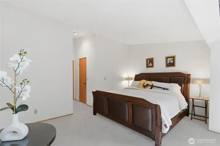 master bedroom with large windows and vaulted ceiling.