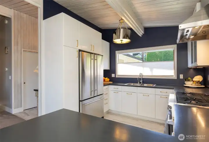 Kitchen overlooks lush gardens, level entry home. Pantry and appliance storage at entrance.