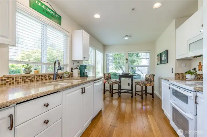 Sunny kitchen features crisp white cabinetry, quartz counters and a double oven.
