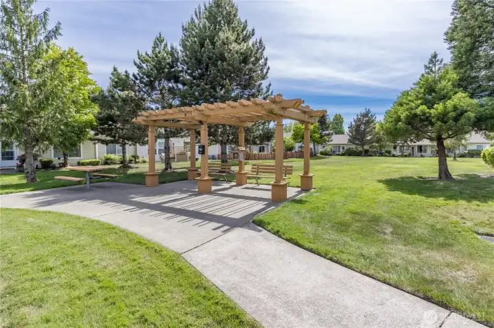 The community features a stunning park-like greenspace, perfect for outdoor gatherings or relaxing under the pergola.