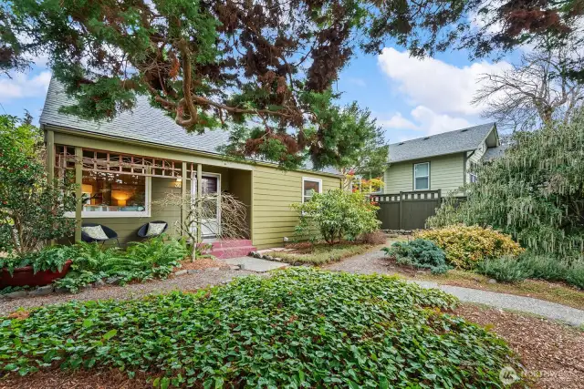 Protected by a majestic cedar, the covered front porch is an ideal spot to enjoy the garden and the changing seasons.