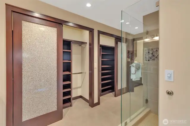 Stylish primary bathroom with large closets and separate toilets.