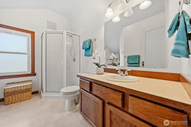 The upper-level Primary bathroom offers both function and comfort, featuring a walk-in shower, large vanity with ample counter space, and abundant natural light.