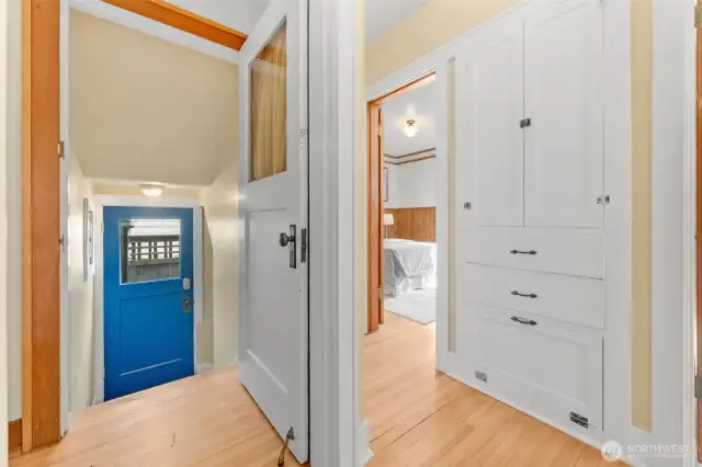 This main-level hallway serves as a central hub, seamlessly connecting the two additional bedrooms with the lower-level basement and side door entry. Don’t miss the charming built-in cabinetry—just one of the many thoughtful storage details found throughout the home!