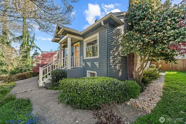 An inviting front porch with rich wood accents and a freshly painted door sets the tone for this beautifully maintained home. Lush landscaping, including a blooming camellia and Japanese maple.