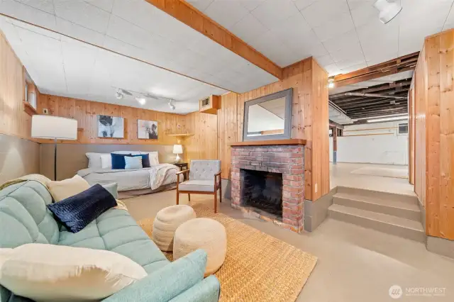 Full of charm, this basement living area features warm wood paneling, a classic wood-burning fireplace, and space to relax, host guests, or unwind by the fire.