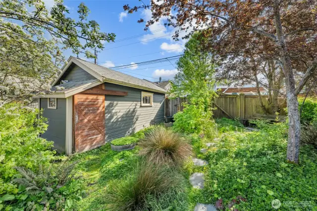 Tucked away in a quiet corner of the yard, this one-car detached garage is surrounded by lush greenery and offers both extra storage and a serene space to garden, tinker, or simply unwind.