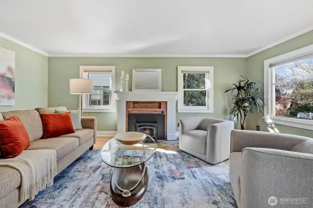This charming living space features a classic wood-burning fireplace and period-matching Marvin double-pane windows. Abundant natural light pours in through multiple windows, creating a warm, inviting atmosphere.