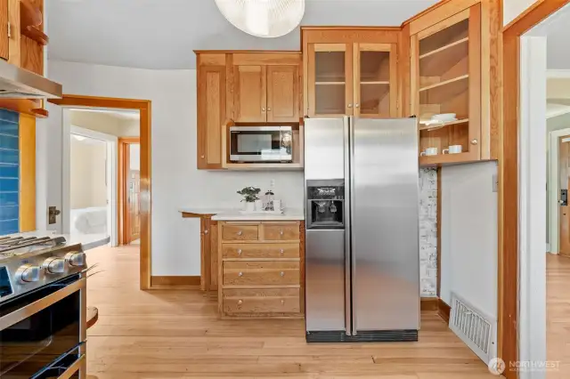 Generous storage in this charming kitchen, complete with stainless steel fridge, built-in microwave, and elegant glass-front cabinets for displaying your favorite pieces.
