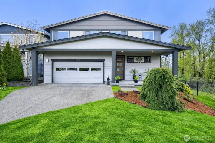 Front-facing exterior on a large corner lot, featuring an expansive driveway with ample parking space and great curb appeal.