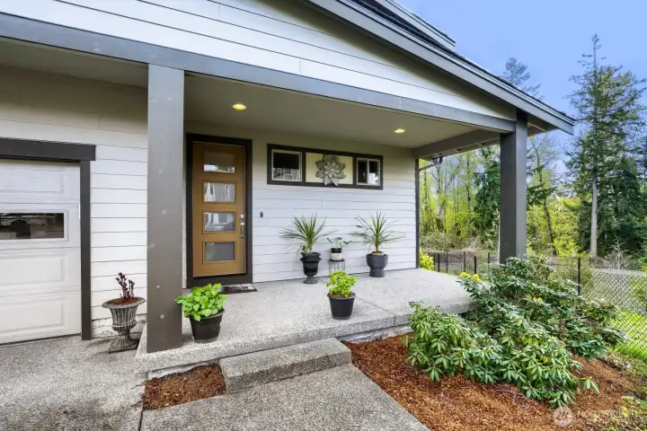 Bright, covered front porch offering a welcoming entrance, perfect for relaxing summer seating or displaying plants.