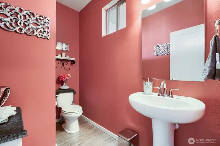 Spacious main-level powder room featuring warm accents and durable luxury vinyl plank flooring throughout.