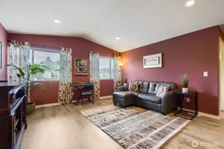 Upper-level living space featuring impressive 12-foot ceilings, stylish accent walls, recessed lighting, and large windows with blinds for comfort and natural light.