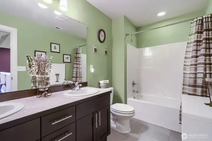 Upper-level full bathroom featuring dual sinks, a relaxing soaking tub, and sleek modern cabinetry.
