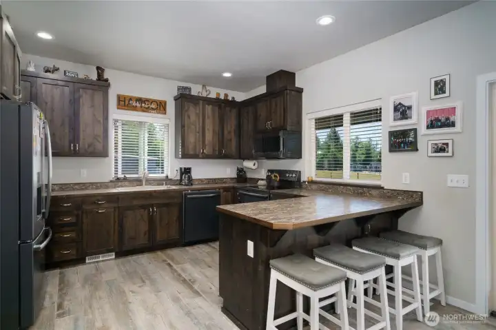 Beautiful dark tone kitchen cabinets accent tile flooring throughout lower level. Peninsula seating for four. Beautiful dark tone kitchen cabinets accent tile flooring throughout lower level. Peninsula seating for four.
