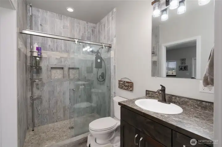 Main floor 3/4 bath with tile shower adjacent to living room and primary bedroom. Main floor 3/4 bath with tile shower adjacent to living room and primary bedroom.