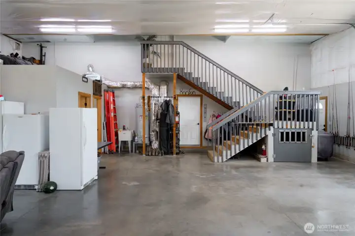 Inside shop looking toward utility and 1/2 bath (left), main house man door (lower) and flex room stairs (upper). Built in dog kennel under the stairs utilizes the space well. Inside shop looking toward utility and 1/2 bath (left), main house man door (lower) and flex room stairs (upper). Built in dog kennel under the stairs utilizes the space well.